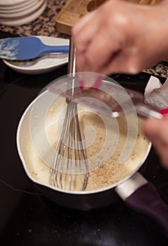Grating nutmeg over bechamel sauce in a pan at home kitchen.