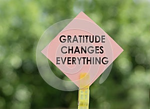 GRATITUDE CHANGES EVERYTHING text on pink note paper on green background