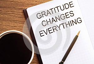 Gratitude changes everything - written in a notebook with a cup of espresso coffee and a pen