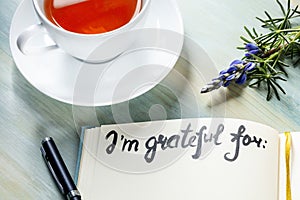 Gratitude journal with a flower and tea, with the handwritten phrase I am grateful for