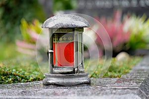 Grave lantern with red memorial candle on a grave