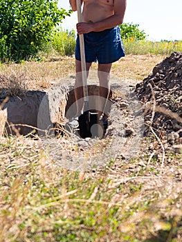 Gravedigger digs a grave. a man digs a hole with a shovel in a cemetery