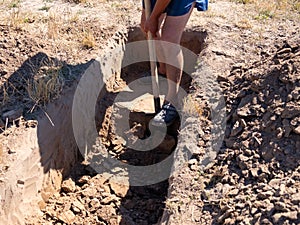 Gravedigger digs a grave. a man digs a hole with a shovel in a cemetery