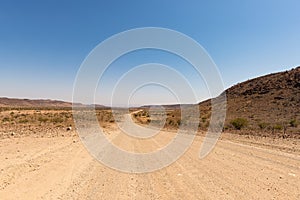 Gravel 4x4 road crossing the colorful desert at Twyfelfontein, in the majestic Damaraland Brandberg, scenic travel destination in