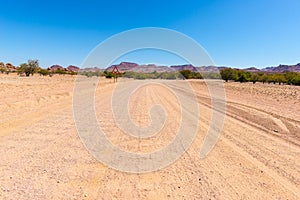 Gravel 4x4 road crossing the colorful desert at Twyfelfontein, in the majestic Damaraland Brandberg, scenic travel destination in