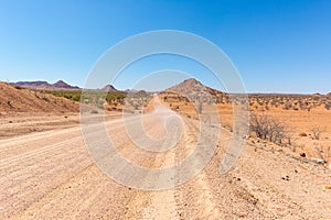 Gravel 4x4 road crossing the colorful desert at Twyfelfontein, in the majestic Damaraland Brandberg, scenic travel destination in