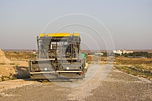 Gravel and asphalt tamping machine stands on the road. road under construction. Gravel poured in the steppe as a