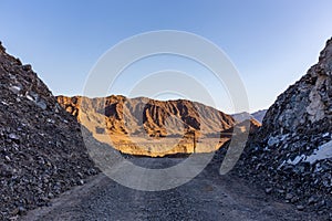 Gravel dirt road through rocky limestone Hajar Mountains and cliffs in United Arab Emirates