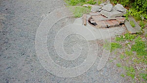 A gravel driveway and a manhole with a stolen cast iron cover. A wooden shield with stones covers the sewer opening. The problem w