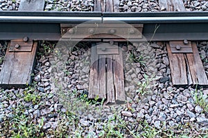 Gravel with grass. Old sleepers, in city there is a tram line. In nature, a wet wooden board. Coupling of metal rails.