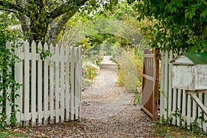 Gravel path leading between tow open gated through old English style garden
