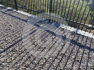 gravel patio stone path evening shadows steel metal garden path fence sunlight sun beams walkway