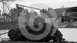 Gravel pit at quarry pond with large rock in foreground in black and white