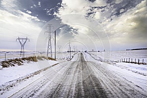 A gravel road along power lines and electrical transmission towers