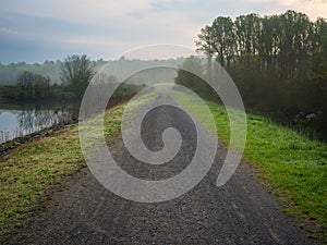 Gravel Road Along Reservoir in Foggy Forest photo