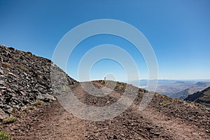 Gravel road on a side of a cliff leading into the sky