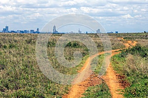 Gravel road towards Nairobi city skyline.