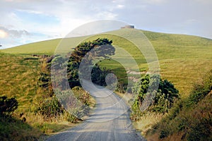 Gravel road turn left at rural area near water tank on hill top