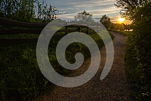 The gravelly path leads to the lake in the sunset