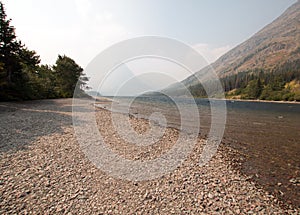 Gravelly shoreline of Upper Two Medicines Lake in Glacier National Park during the 2017 fall forest fires in Montana USA