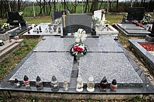 Graves, tombstones and crucifixes on traditional cemetery. Votive candles lantern and flowers on tomb stones in graveyard