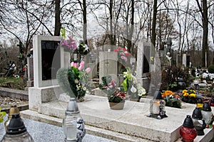 Graves, tombstones and crucifixes on traditional cemetery. Votive candles lantern and flowers on tomb stones in graveyard