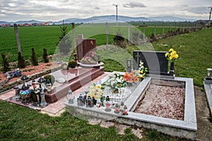 Graves, tombstones and crucifixes on traditional cemetery. Votive candles lantern and flowers on tomb stones in graveyard