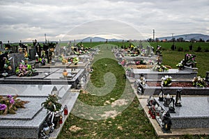 Graves, tombstones and crucifixes on traditional cemetery. Votive candles lantern and flowers on tomb stones in graveyard