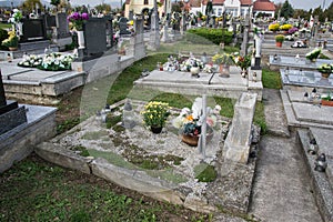 Graves, tombstones and crucifixes on traditional cemetery. Votive candles lantern and flowers on tomb stones in graveyard