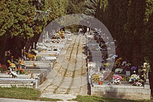 Graves, tombstones and crucifixes on traditional Slovak cemetery. Votive candles lantern and flowers on tomb stones in graveyard