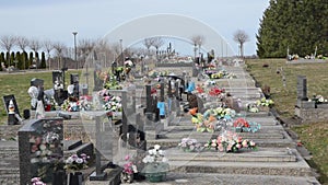 Gravestones and flowers in Catholic Cemetery. Graves and Tombstones. Black headstones in graveyard. Floral decoration and tombs. M