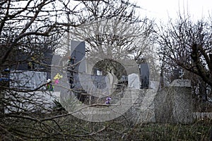 Gravestones, monuments and crosses in a Christian cemetery among tree branches. Eternal memory and sorrow
