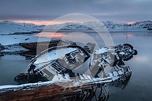 Graveyard of old ships on the shore the frozen Barents Sea