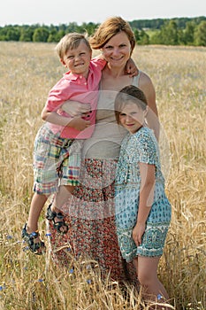 Gravid mother with children in rye field in a sunny windy day