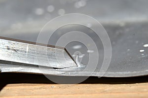 Graving tool in use on a sheet of lead, it can be seen how it has raised a chip of metal