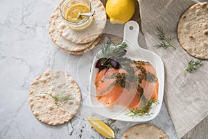 Gravlax a raw, marinated graved salmon with dill on plate with crispbread, Scandinavian mustard sauce, lemon and linen towel on