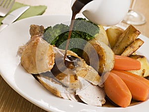 Gravy being Poured over a plate of Roast Chicken photo