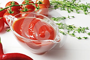 Gravy boat filled with delicious tomato sauce, a branch of fresh cherry tomatoes