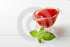 Gravy boat filled with delicious tomato sauce on a white wooden