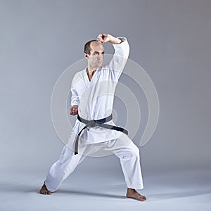 On a gray background the athlete trains the block with his hand in a formal karate exercise