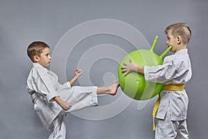 On a gray background, a boy is training a kick on a green ball