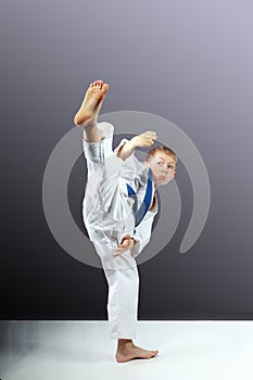 On a gray background little boy is beating mawashi geri