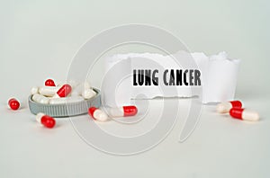 On a gray background, medical capsules and a paper plate with the inscription - Lung cancer