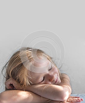 On a gray background a sleeping smiling girl lies in the rays of the sun morning