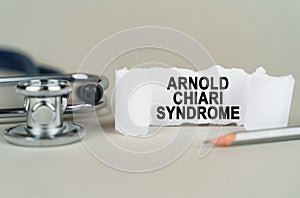 On a gray background, a stethoscope, a pencil and a paper plate with the inscription - Arnold chiari syndrome photo