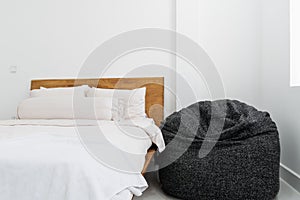 Gray bean bag inside bedroom next to comfy bed. Minimalist bedroom interior design.