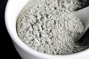 Gray bentonite clay powder in a bowl. Diy facial mask and body wrap recipe. Natural beauty treatment and spa. Selective focus