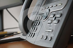 Gray and black business wired phone with receiver, dial and large display in the business office environment