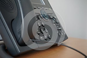 Gray and black business wired phone with receiver, dial and large display in the business office environment