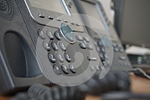 Gray and black business wired phone with receiver, dial and large display in the business office environment